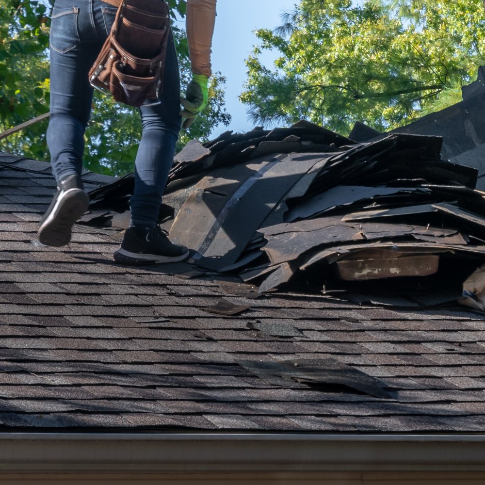 Roofing technician repairing damaged shingles on Milwaukee home after a spring storm to prevent future leaks