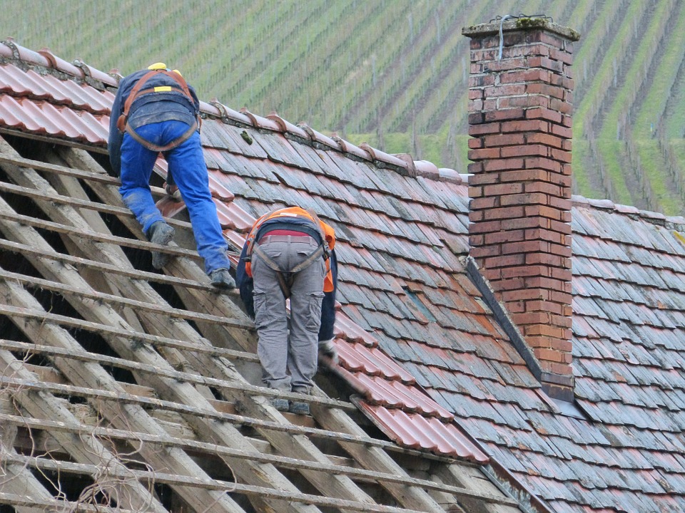 Emergency crew repairing storm-damaged roof on Franklin, WI home during heavy rain for immediate leak control